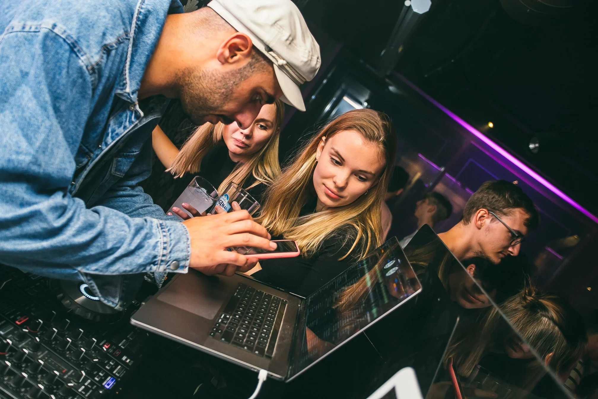 DJ Snabu katsomassa juhlavieraan puhelinta DJ-pöydän ääressä