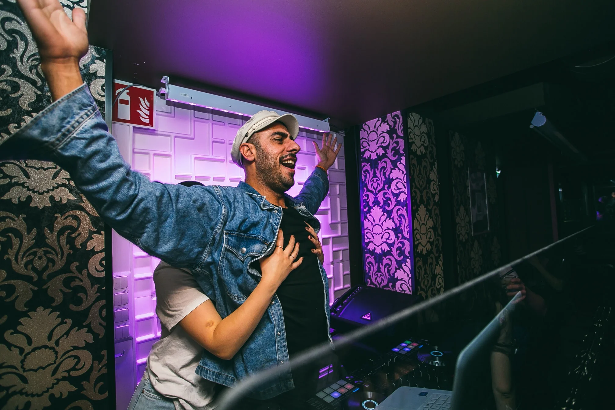 DJ Snabu kädet kohotettuina ravintolan DJ-pisteellä
